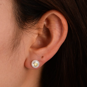 S925 silver natural pearl stud earrings with gold heart detail worn on a person's ear