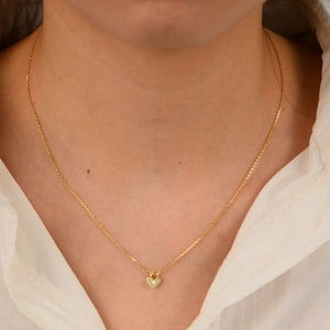 Collier élégant avec pendentif cœur doré et zircon porté par un mannequin en chemise