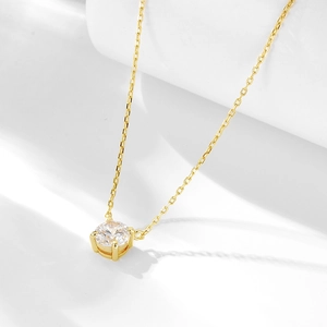 Détail d'un collier doré minimaliste avec un pendentif en zircone cubique à quatre griffes