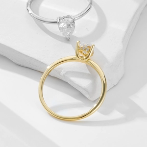 Detail of pear-cut and round-cut cubic zirconia rings on white textured stone background
