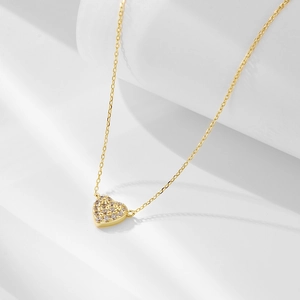 Close-up of gold s925 silver heart pendant necklace with shimmering zircon micro-pave