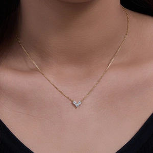 Gros plan d'un collier en argent s925 doré avec trois diamants étincelants en cœur