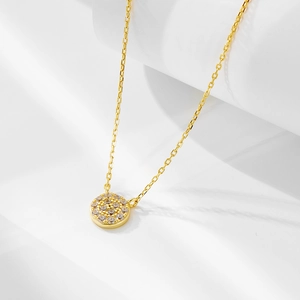 Gros plan d'un pendentif en argent doré avec zircon serti pavé sur un support blanc épuré