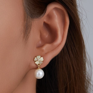 Elegant gold clover earrings with sparkling pavé diamonds and round pearl drop on model