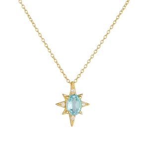 Collana a stella a otto punte in oro con ciondolo in topazio azzurro su sfondo bianco