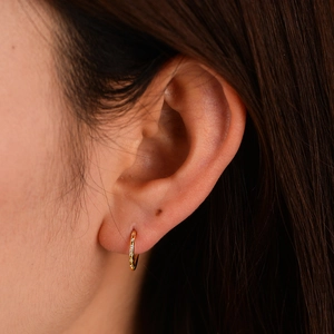 Macro shot of gold S925 sterling silver huggie earrings with cubic zirconia stones