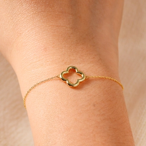 Close-up of a minimalist gold hollowed-out four-leaf clover charm bracelet for women