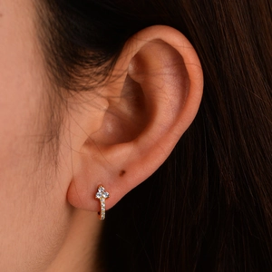 Close-up of gold 925 silver huggie earrings with sparkling triangular zircon clusters