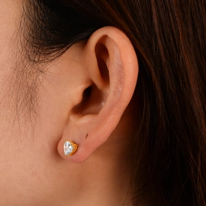Macro shot of heart-shaped zircon earrings with gold plating on ear for detailed view
