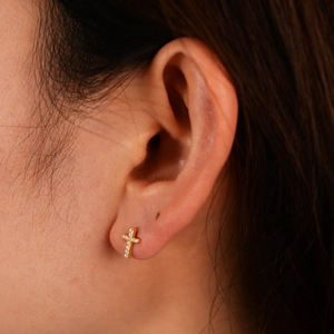 Detail of s925 silver cross stud earring with zircon inlay worn on an ear