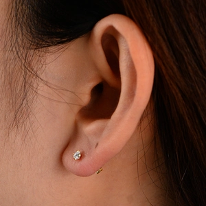 Close-up of 3mm zircon stud earring with four-claw gold setting on model's ear