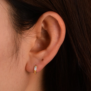 Macro detail of gold plated S925 silver hoop earring with rectangular zircon on ear