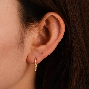 Close-up of a gold s925 sterling silver hoop earring with oval zircon stones on ear
