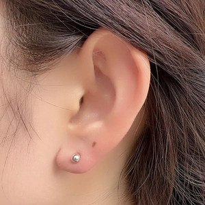 Close-up of minimalist S925 sterling silver ball stud earring worn on the earlobe