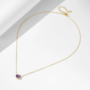 Macro shot of S925 sterling silver tag and amethyst pendant on a sleek gold chain