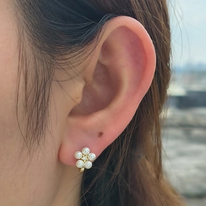 Detailed view of S925 silver flower stud earring with pearls and central crystal on ear