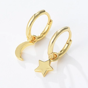 Détail de boucles d'oreilles asymétriques en argent S925 doré avec breloques lune et étoile