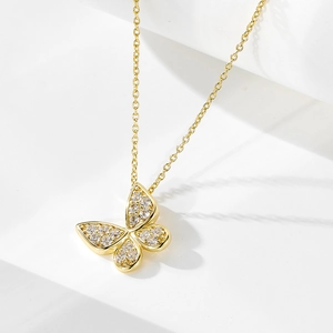Vue rapprochée d'un collier pendentif papillon doré orné de zircons sur des marches blanches