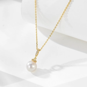 Macro view of a white round pearl pendant with sparkling diamonds and gold chain