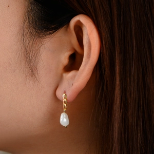 Detail of 925 silver gold chain drop earrings with natural baroque pearls on model