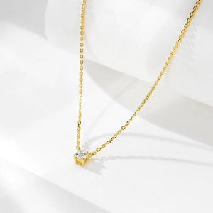 Detailed view of the four-prong setting holding a round brilliant gemstone on a gold chain