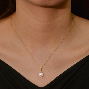Elegant natural pearl necklace with gold chain and tiny diamonds worn on neck