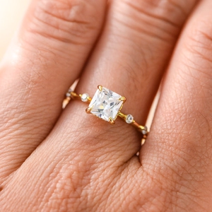 Macro shot of princess cut cubic zirconia ring with gold wavy band and side diamonds