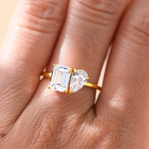 Toi et Moi gold ring with emerald and pear cut zircon stones on a model's finger