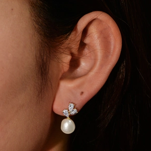 Close-up of elegant s925 silver pearl drop earrings with sparkling zircon flower on a model