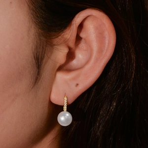 Close-up of elegant s925 silver pearl earring with gold accents on female model