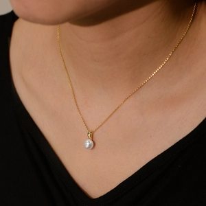 Detail of elegant gold S925 necklace with natural freshwater pearl pendant on collarbone