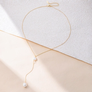 Elegante goldene S925 Silber Y-Kette mit zwei Barockperlen auf einer Steinoberfläche