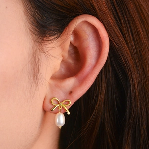 Elegant s925 silver bow and freshwater pearl drop earrings worn on a female model