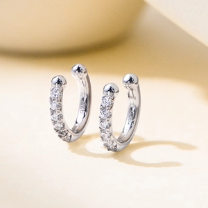 Manchette d'oreille en argent S925 avec zircons brillants sur fond beige minimaliste