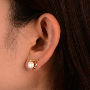 Modella che indossa un orecchino a perno con perla naturale e montatura d'oro
