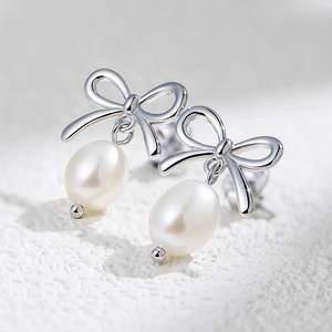 Close-up of S925 silver bow stud earrings with lustrous natural freshwater pearls