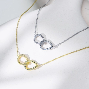 Detailed view of intertwined twisted silver and smooth gold rings on an elegant necklace