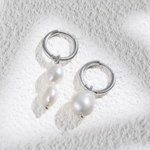 Macro detail of asymmetric silver earrings featuring white baroque freshwater pearls
