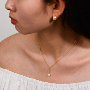 Close-up of a s925 silver pearl pendant necklace and matching studs on a model