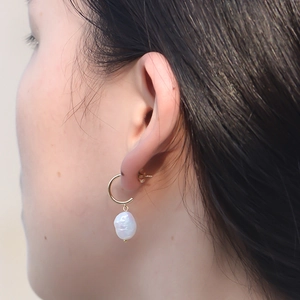 Close-up of elegant s925 silver baroque pearl drop earrings worn by a female model