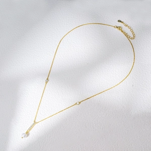 Detail of s925 gold necklace with geometric bar pendant and round white pearl charm