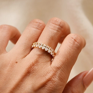 Close-up of gold eternity ring featuring oval-cut cubic zirconia in a prong setting