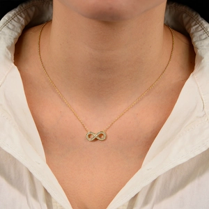 Collier symbole infini doré avec oxydes de zirconium porté par un mannequin femme