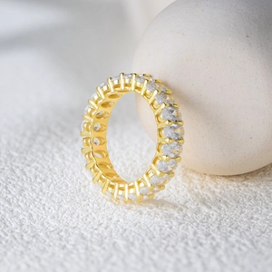 Elegant gold eternity ring with round cubic zirconia in a claw setting on light stones