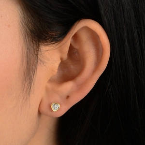 Elegant gold heart stud earrings with cubic zirconia stones worn by a model