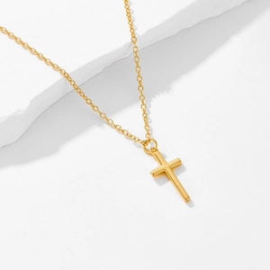 Minimalist gold cross pendant necklace on silver O-chain over textured white stone