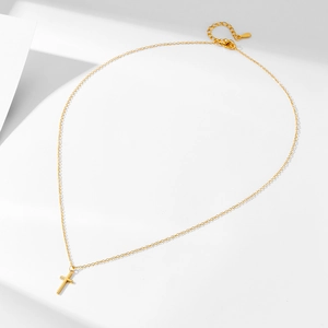 Minimalist sterling silver cross necklace with polished gold finish on a white background