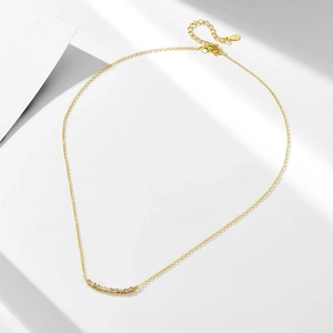 Macro d'un collier en argent S925 doré avec pendentif incurvé et pierres de zircone