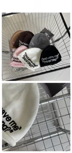 Detail of embroidered slogan on various colored knit beanies in a metal cart