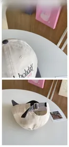 Detail view of the holiday embroidery and vintage metal buckle on the baseball cap